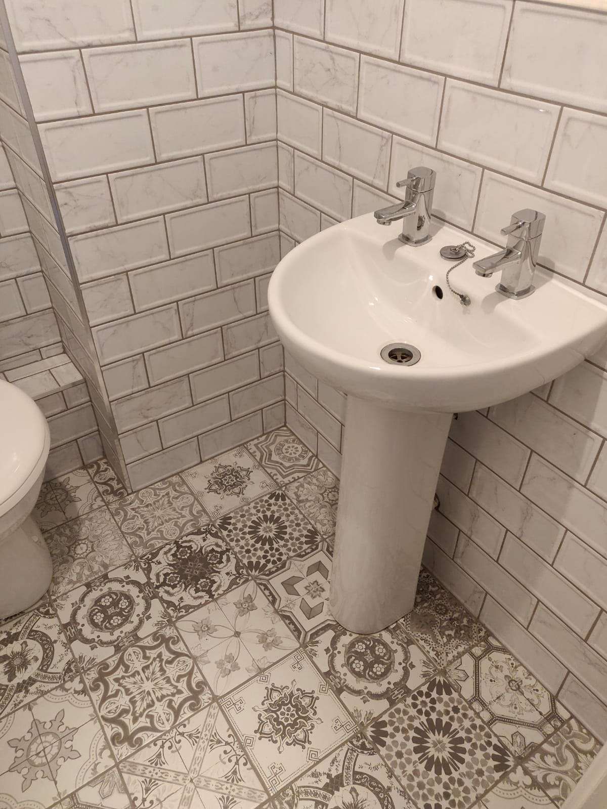 Bathroom with pedestal basin, subway tiles and patterned floor