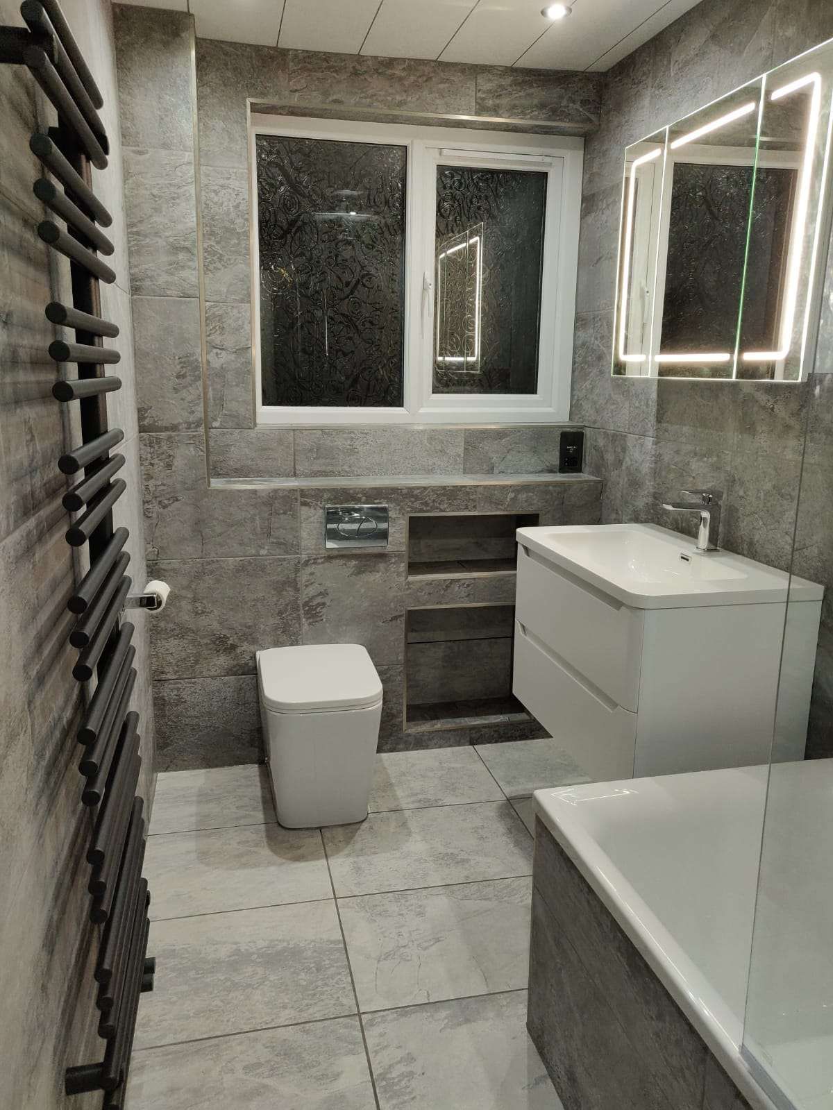 Grey bathroom with twin LED mirrors, vanity and bath