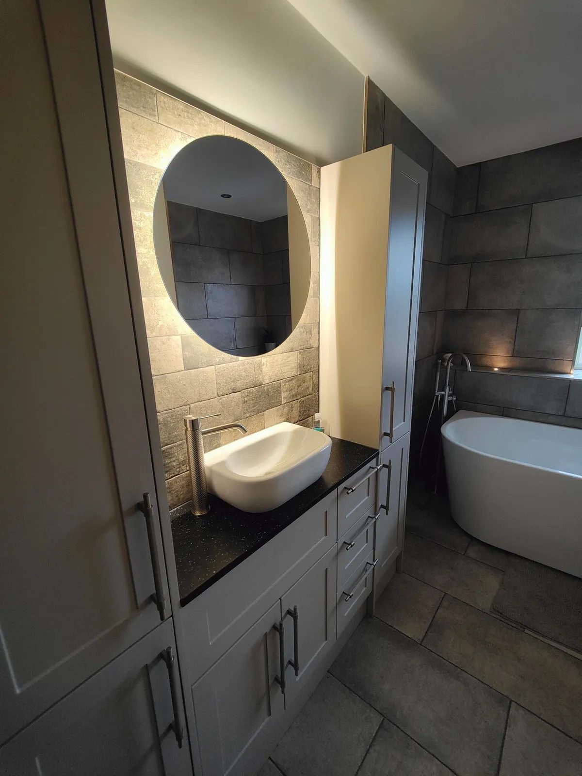 Modern bathroom with round LED mirror, floating basin and freestanding bath
