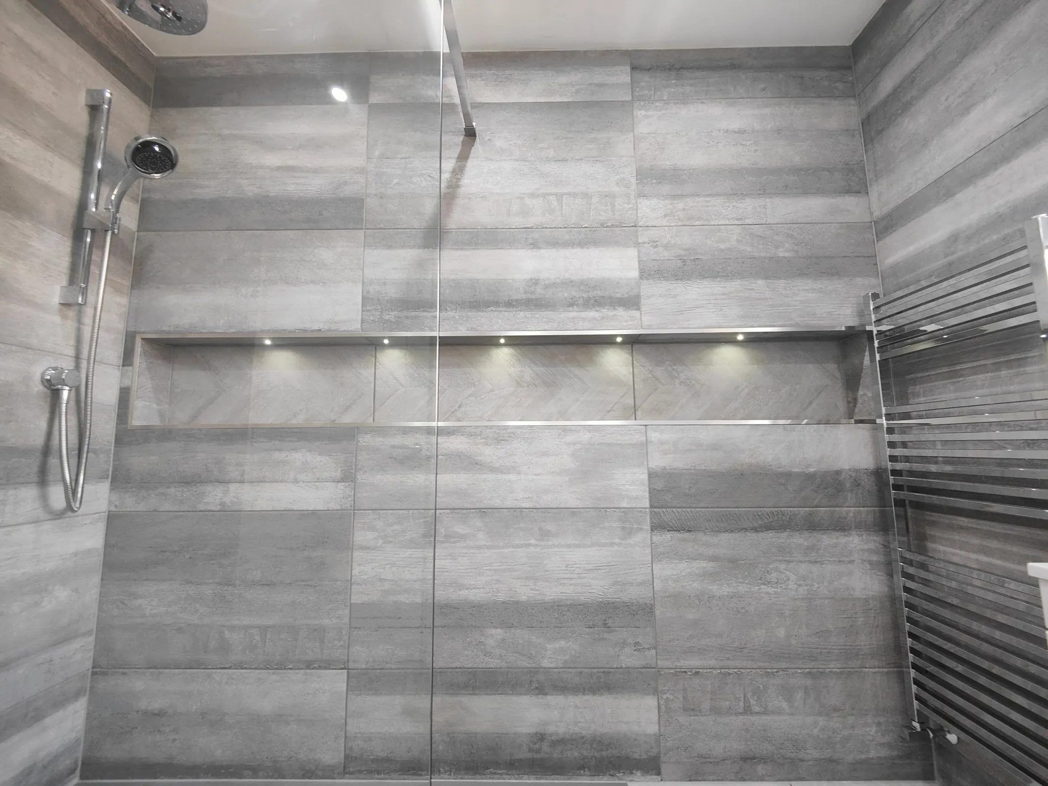 Grey tiled shower area with alcove and strip lighting